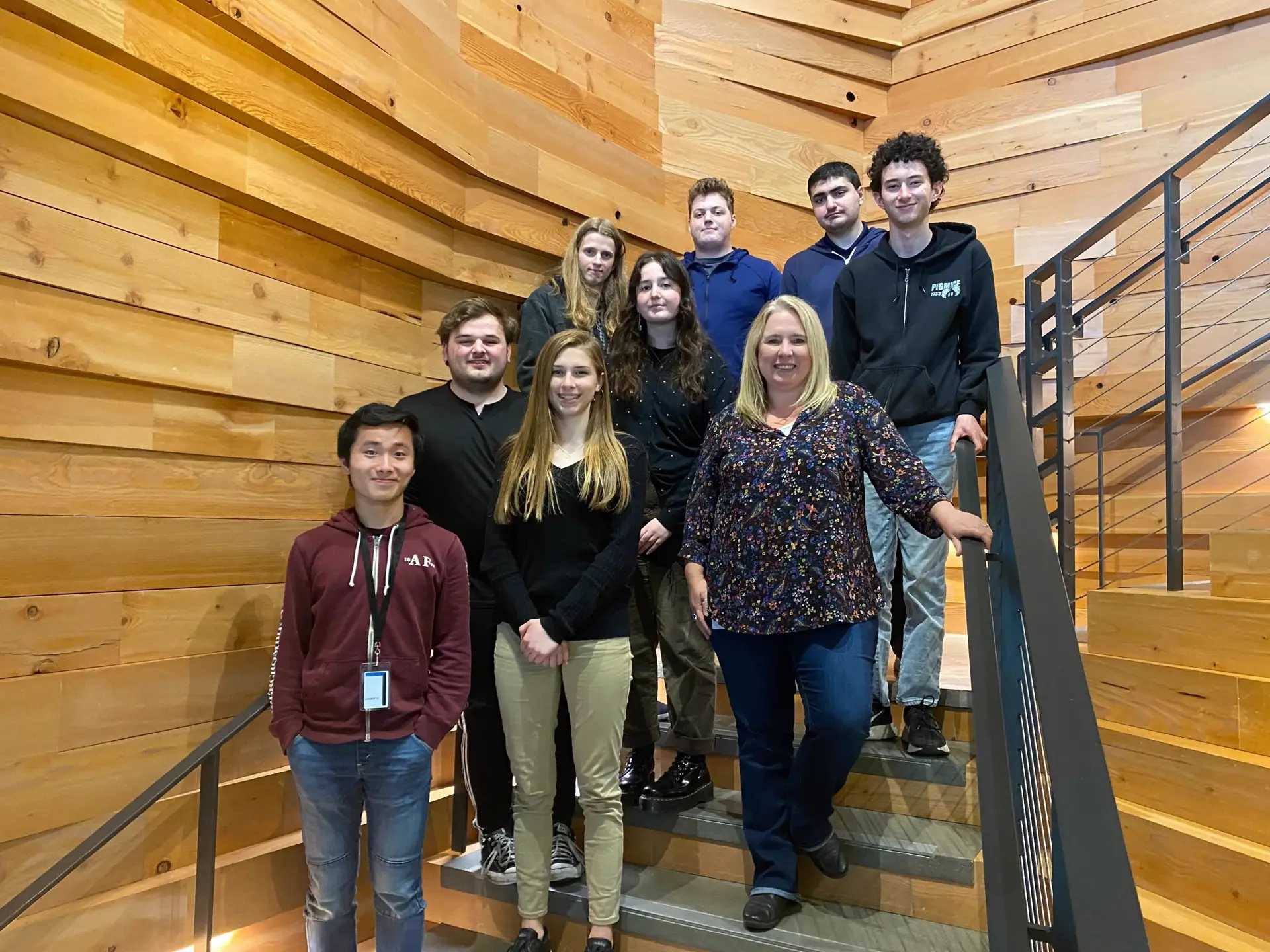 A group of 9 people standing in a stairwell looking at the camera