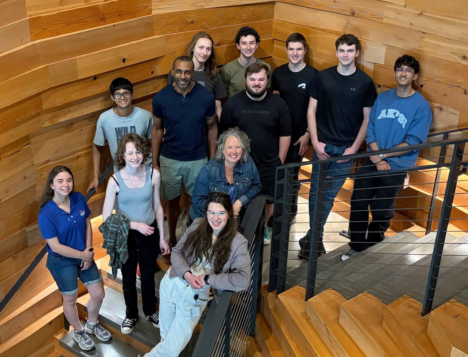 A group of 12 people standing in a stairwell looking at the camera.