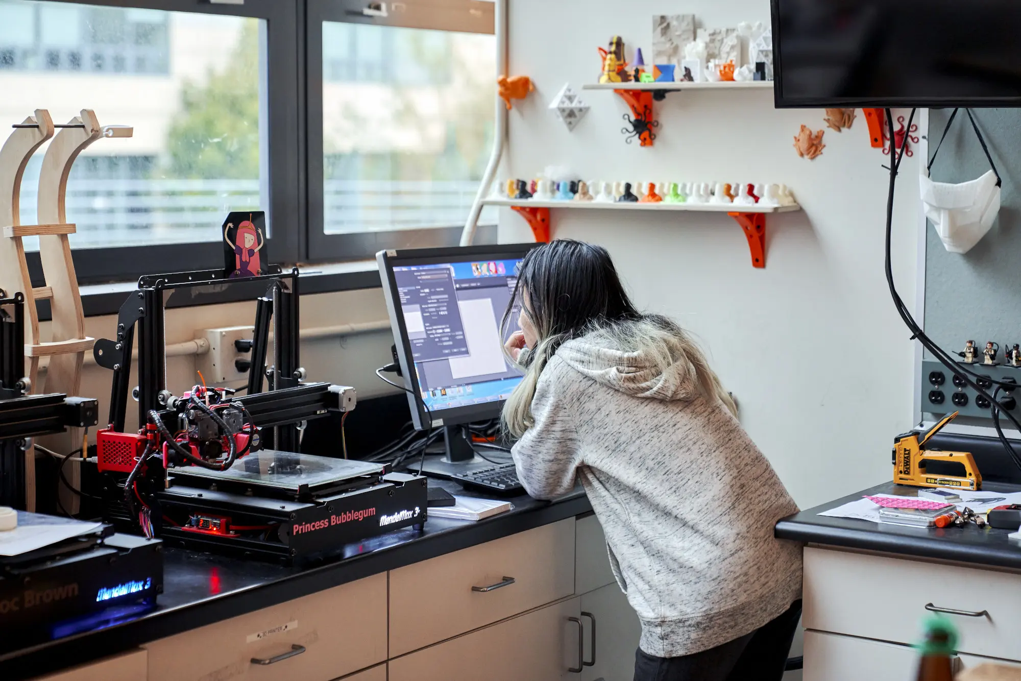 Person using a computer, with a 3d printer next to them